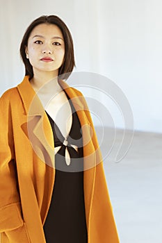 Portrait of a young Chinese woman wearing a nice orange coat and a black skintight dress photo