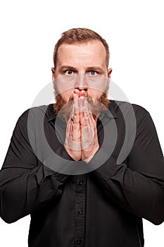 Portrait of a young, chubby, redheaded man in a black shirt making faces at the camera, isolated on a white background