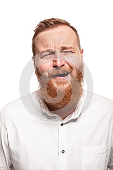 Portrait of a young, chubby, redheaded man in a white shirt making faces at the camera, isolated on a white background
