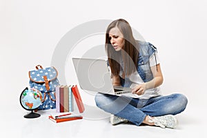 Portrait of young concerned puzzled woman student holding using laptop pc computer sitting near globe, backpack, school