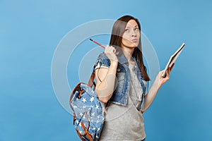 Portrait of young concerned woman student in denim clothes with backpack taking exam thinking about test hold notebook