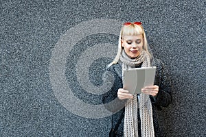 Portrait of young confident fashionable freelance woman with cool attitude working on digital tablet outside office building.