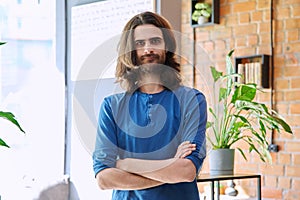 Portrait of young confident handsome man with crossed arms, looking at camera