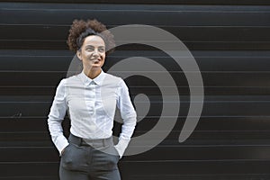 Portrait of young confident successful business woman standing outside office building. Educated independent female team leader