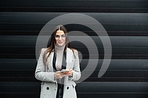 Portrait of young confident successful business woman standing outside office building. Educated independent female team leader