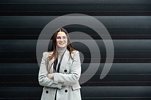 Portrait of young confident successful business woman standing outside office building. Educated independent female team leader