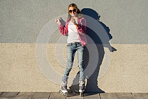 Portrait of young cool girl, shod in rollerblades holding chocol