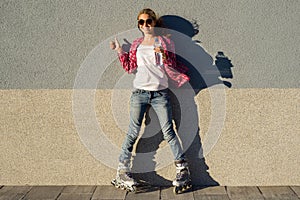 Portrait of young cool smiling girl shod in rollerblades, holdin