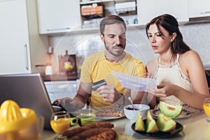 Young couple calculating bills at home