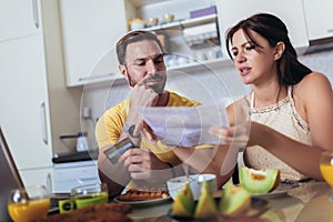 Young couple calculating bills at home