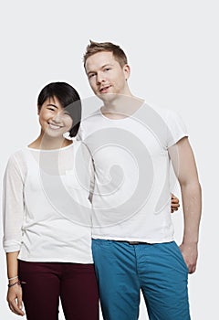 Portrait of young couple in casuals smiling over white background