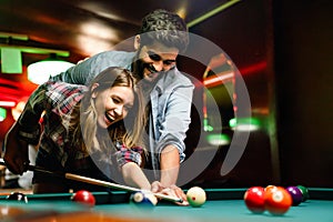 Portrait of young couple having fun playing billiard together.