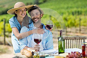 Portrait of young couple holding red wine at table