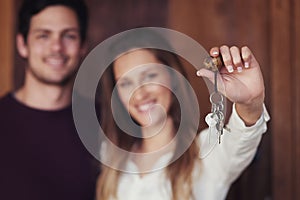 The keys to our home sweet home. Portrait of a young couple holding up the keys to their new home.