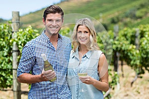 Portrait of young couple holding wine bottle and glass