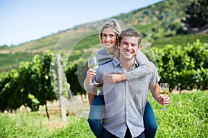 Portrait of young couple holding wineglasses while piggybacking