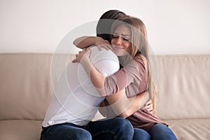 Portrait of young couple hugging tight sitting on couch indoors