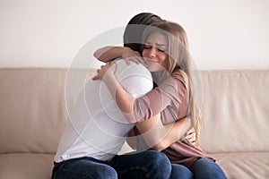 Portrait of young couple hugging tight sitting on couch indoors photo
