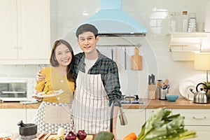 Portrait young couple in love helping to cook In a romantic atmosphere at home and looking at camera with smile face