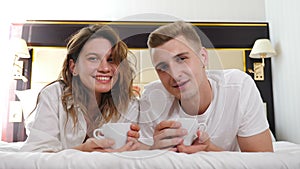 Portrait of young couple lying on bed and smiling at camera. Happy relationship. romantic scene in bedroom at home or