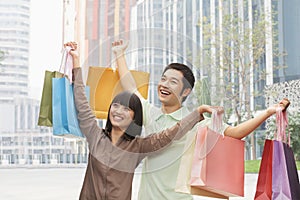 Portrait of young couple posing with shopping bags in hands, Beijing, China