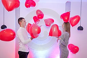 Portrait of young couple with red shape heart air balloons. Valentine`s day celebration concept