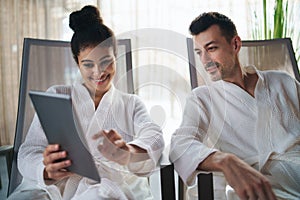 Portrait of young couple relaxing in spa resort, using tablet.