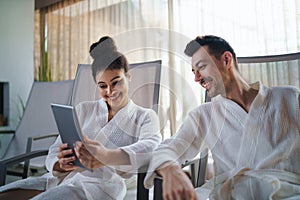 Portrait of young couple relaxing in spa resort, using tablet.