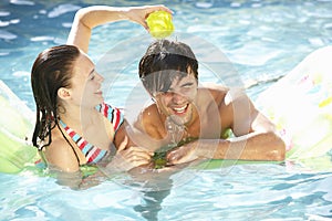 Portrait Of Young Couple Relaxing In Swimming Pool