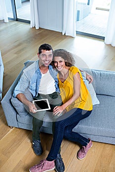 Portrait young couple sitting on sofa and using digital tablet
