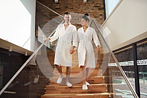 Portrait of young couple in spa resort, walking down the stairs.