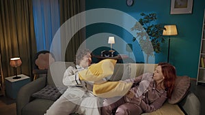 Portrait of young couple spending time together. Man and woman in pajamas sitting on the sofa, talking and start a