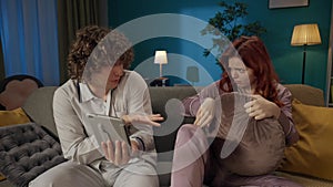 Portrait of young couple spending time together. Man and woman in pajamas sitting on the sofa, watching scary movie on