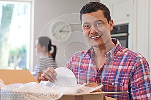 Portrait Of Young Couple Unpacking Boxes In Kitchen On Moving Da