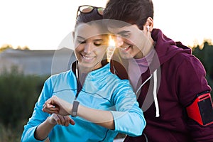 Portrait of young couple using they smartwatch after running.