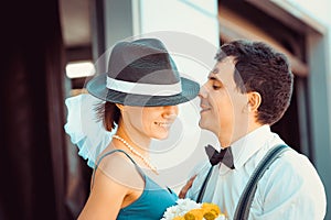 Portrait of a young couple in wedding attire celebrating their wedding anniversary. Smile, kiss, holding the bouquet together