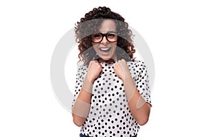 portrait of a young curly brunette well-groomed slender lady dressed in polka dot blouse in black and white