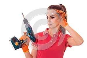 Portrait of young cute brunette builder girl makes renovation with drill in hands isolated on white background