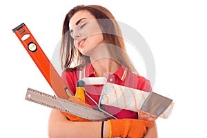 Portrait of young cute brunette builder girl makes renovation with tools in hands isolated on white background