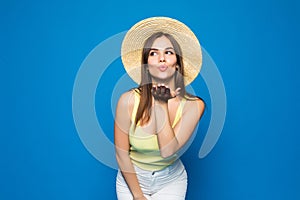 Portrait of a young cute woman blowing kiss at camera isolated on the blue background