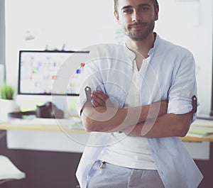 Portrait of young designer in front of laptop and computer while working. Assistant using her mobile at background.