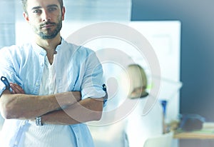 Portrait of young designer in front of laptop and computer while working. Assistant using her mobile at background.