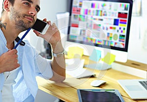 Portrait of young designer sitting at graphic studio in front of laptop and computer while working online.