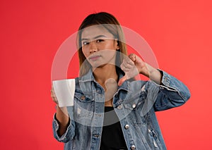 Young dissapointed attractive asian girl holding coffee with thumbs down in studio photo