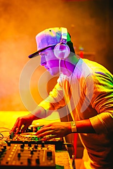 Portrait of Young DJ playing mixing music at night party under colorful lights.