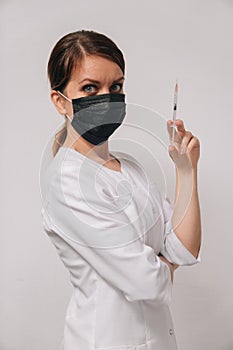 Portrait of a young doctor in her hands with a syringe. vertical snapshot of the nurse who treats the patient