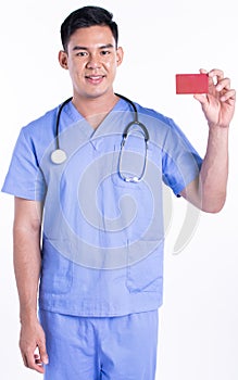 Portrait of young doctor smiling, holding credit card and standing on white background