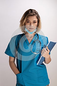 Portrait of young doctor with stethoscope holding paper results and standing straight with right hand in her pocket