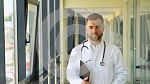 Portrait of young doctor walking on hospital corridor. Successful head physician at clinic