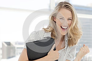 Portrait of a young ecstatic woman holding folder